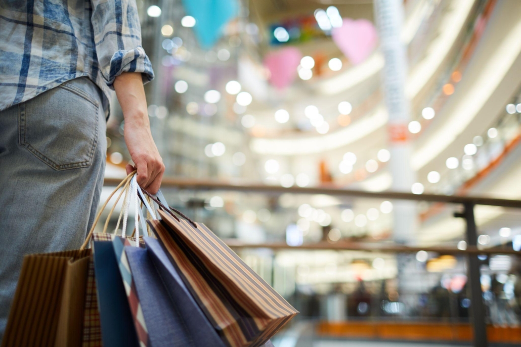 woman in spacious shopping mall and holding many paper bags