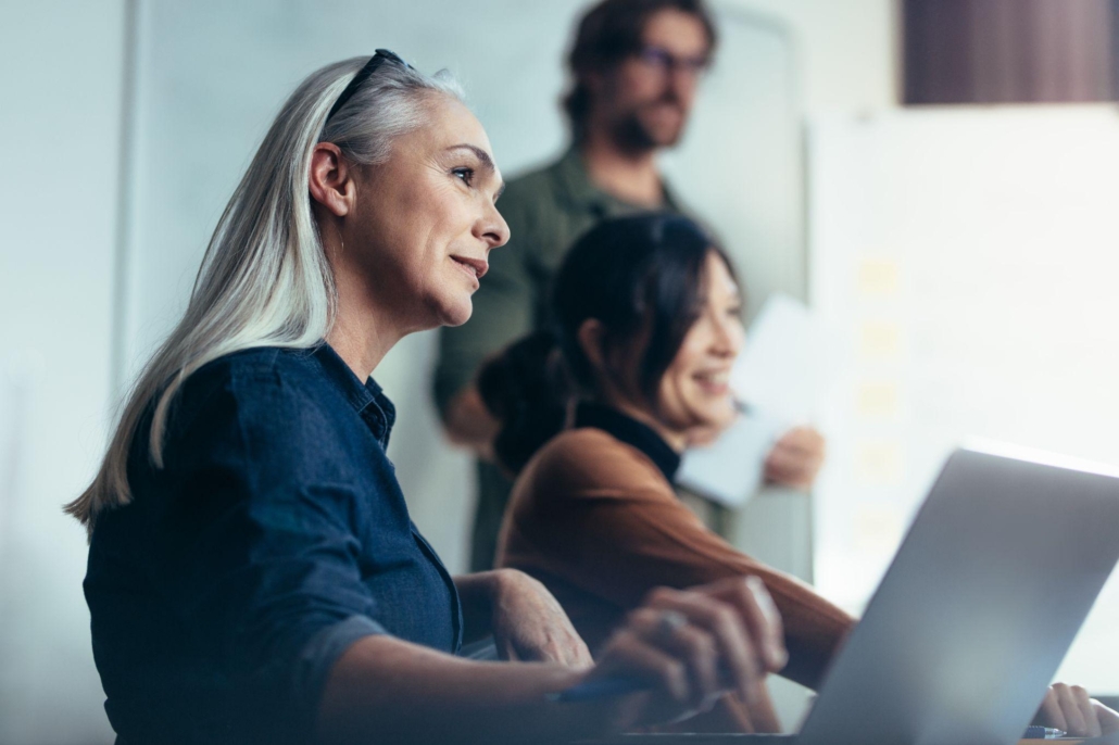 Senior woman with colleagues sitting by during business presentation